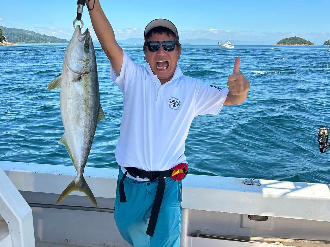 船上で釣り上げた魚を掲げる様子
